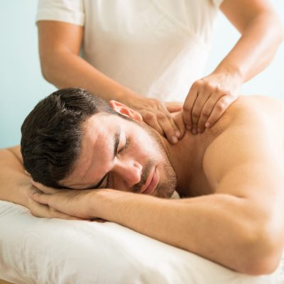 Very relaxed young Latin man getting a deep tissue massage on his back in a wellness and spa clinic